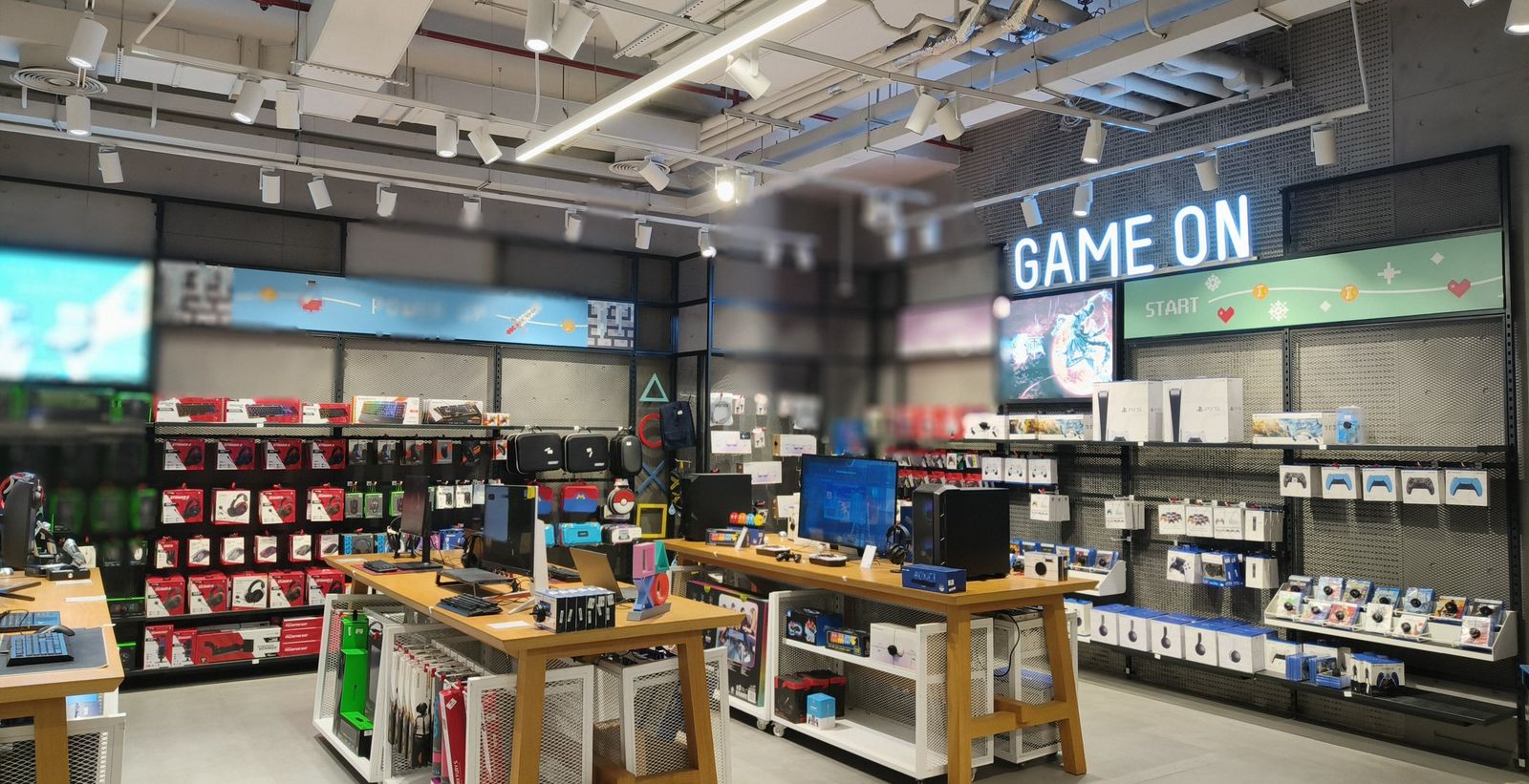 Gaming and electronics retail zone fitted out by PROJECTA, with timber display tables, wall fixtures and illuminated signage